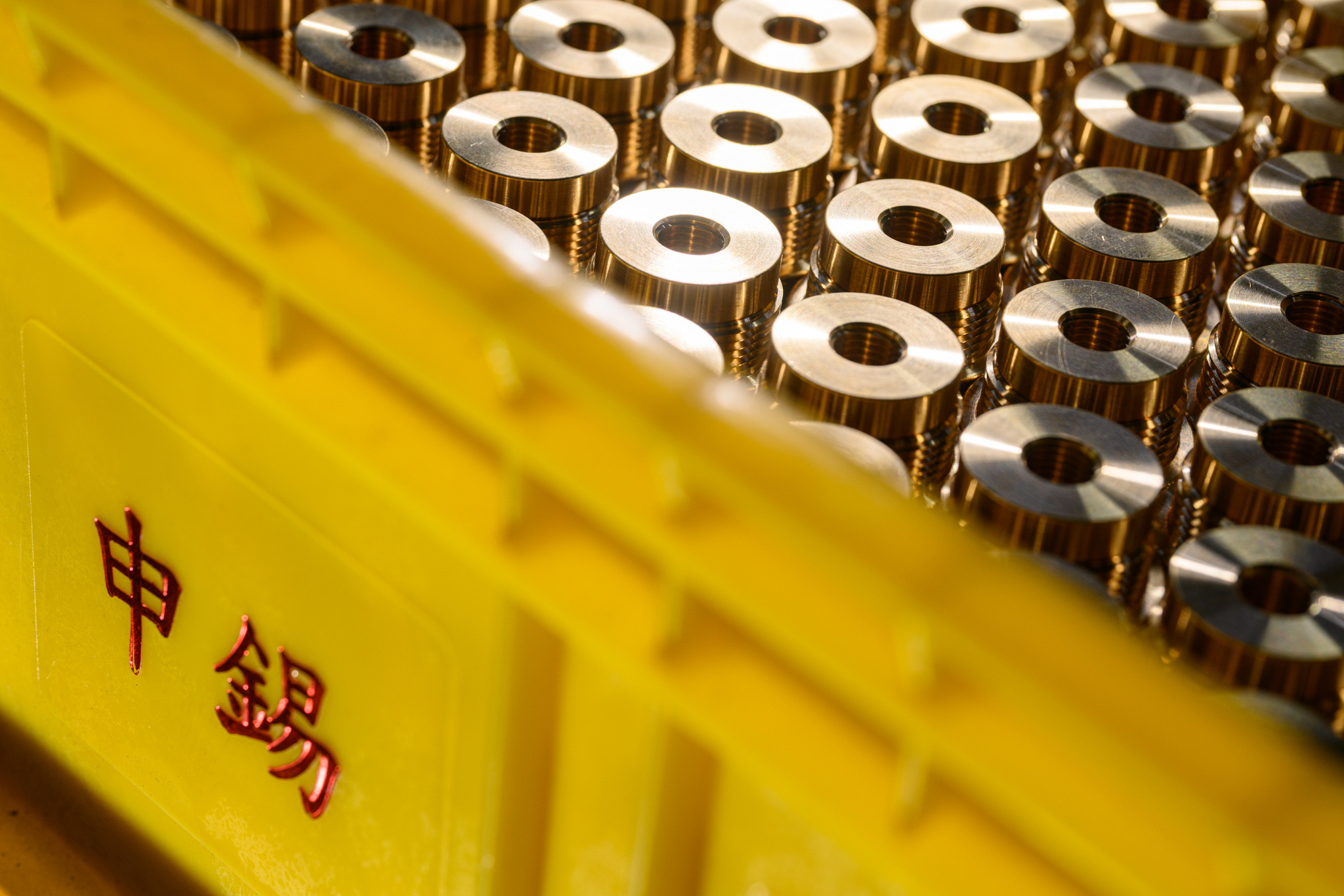Machined brass parts in a yellow Hopeet crate