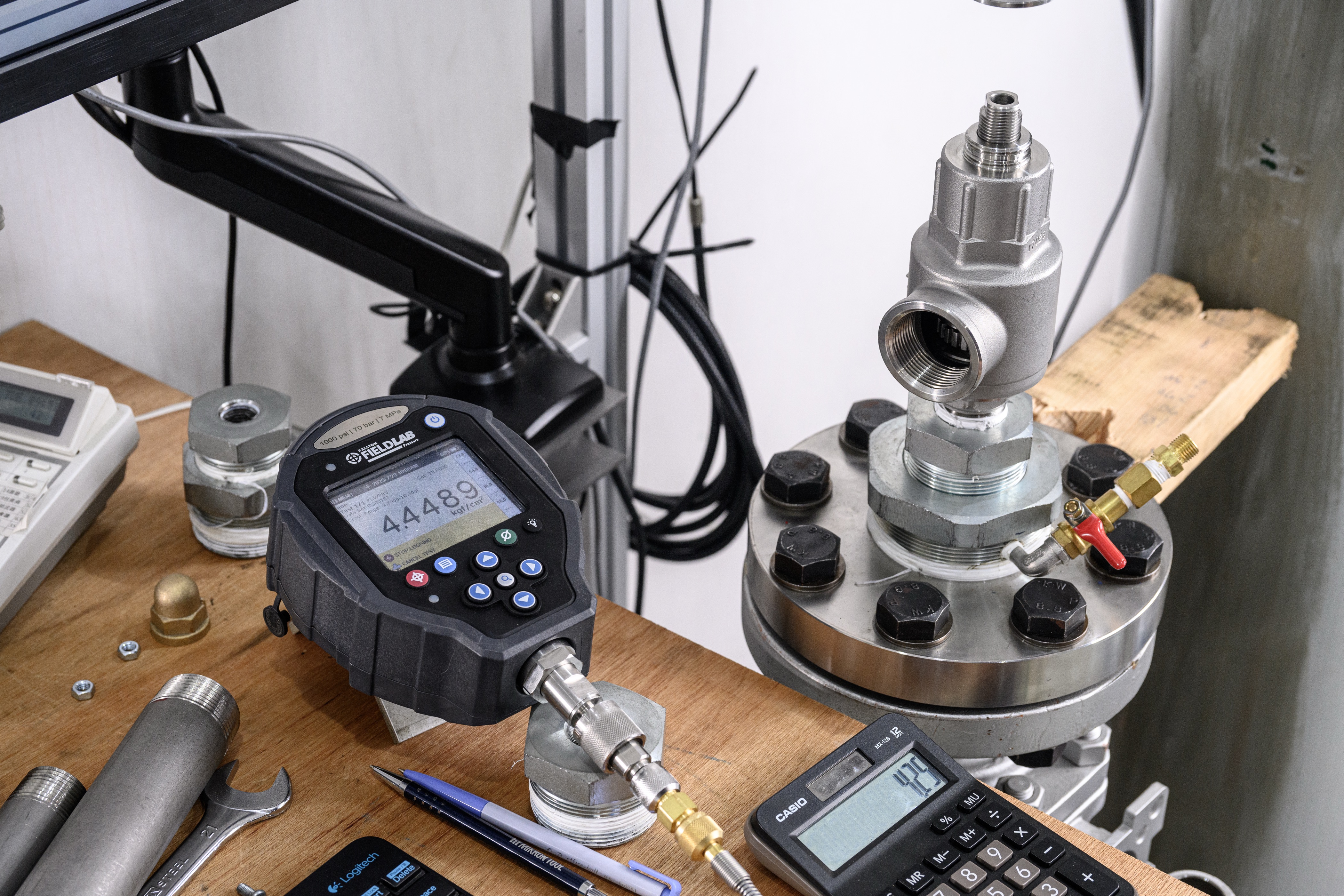 A stainless safety valve mounted on a flange test fixture with a digital pressure gauge